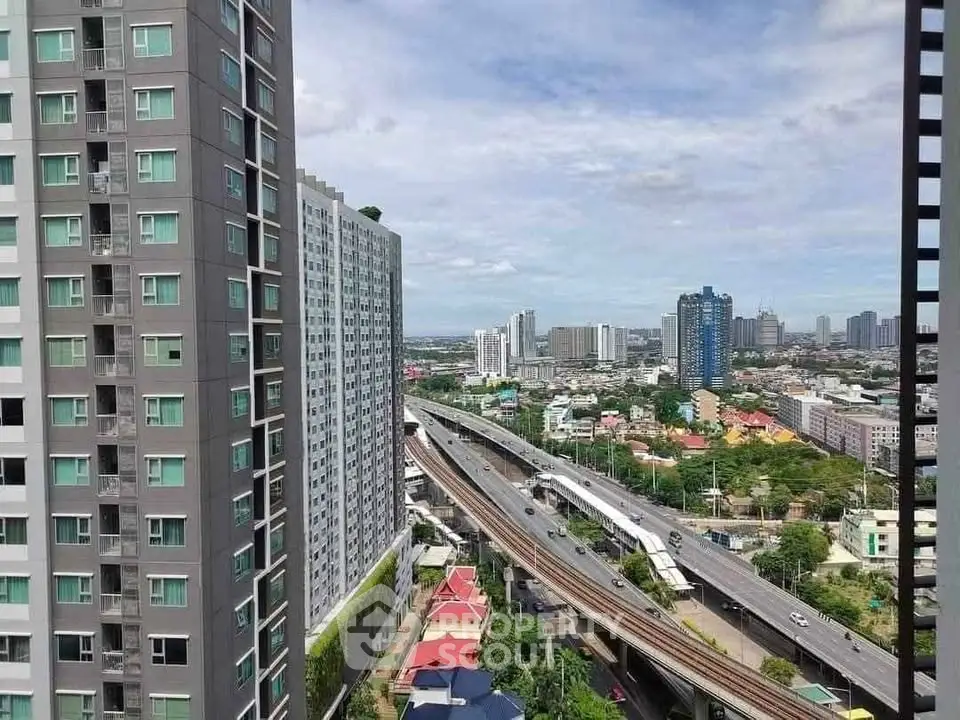 Stunning cityscape view from high-rise apartment overlooking urban skyline and highway.