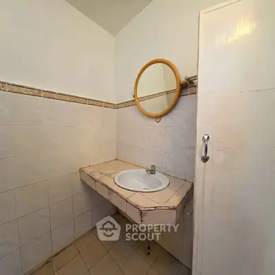 Simple bathroom with tiled sink and round mirror, ideal for minimalist living.