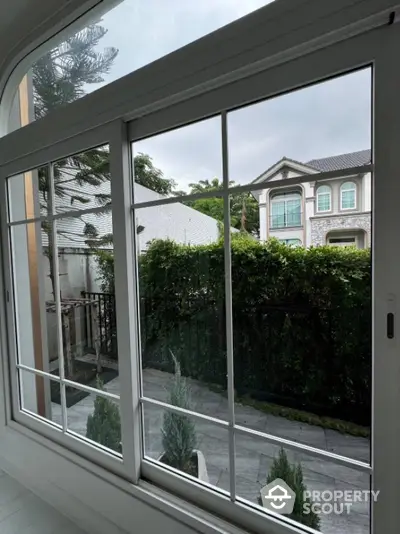 Elegant view from window showcasing lush garden and luxury homes