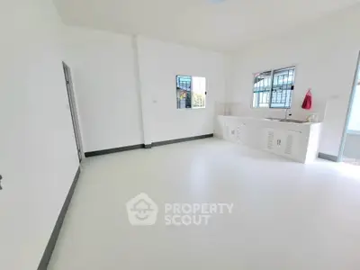 Spacious white kitchen with minimalist design and ample natural light.