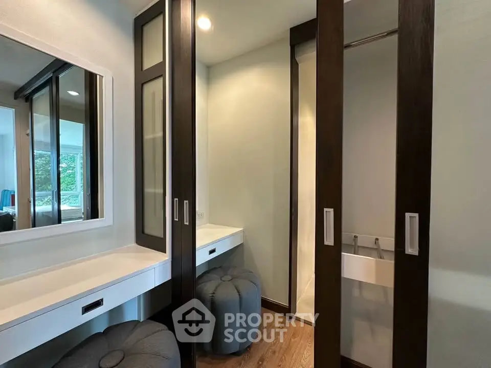 Stylish modern dressing area with mirrored closets and elegant seating in a luxurious home.