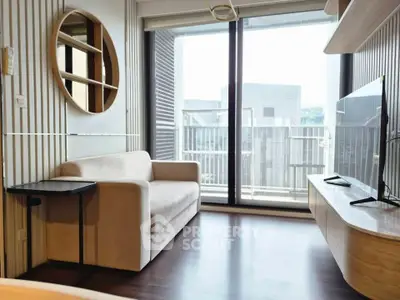 Modern living room with sleek furniture and large windows opening to a balcony with urban view.