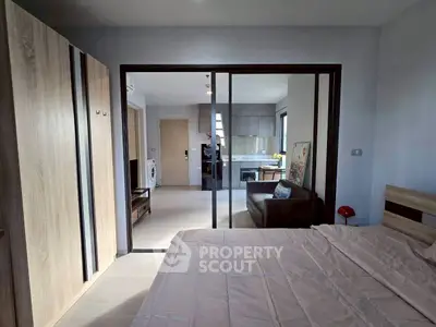Modern apartment interior with bedroom and open kitchen layout, featuring sleek furniture and ample natural light.
