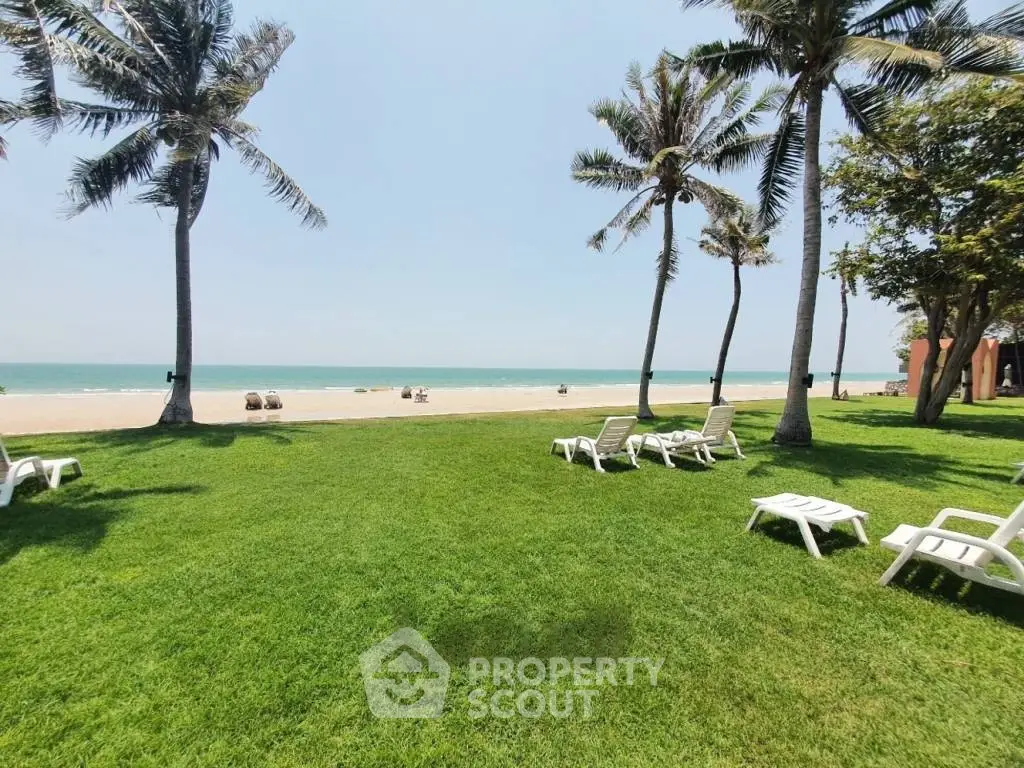 Stunning beachfront property with lush green lawn and palm trees, perfect for relaxation and seaside living.