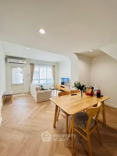 Modern living room with dining area, featuring wooden flooring and stylish furniture.