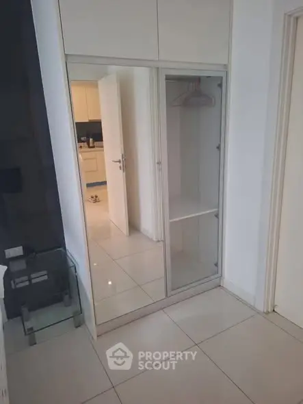 Modern apartment hallway with mirrored closet and view into kitchen