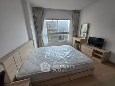 Modern bedroom with large window, natural light, and stylish wooden furniture.