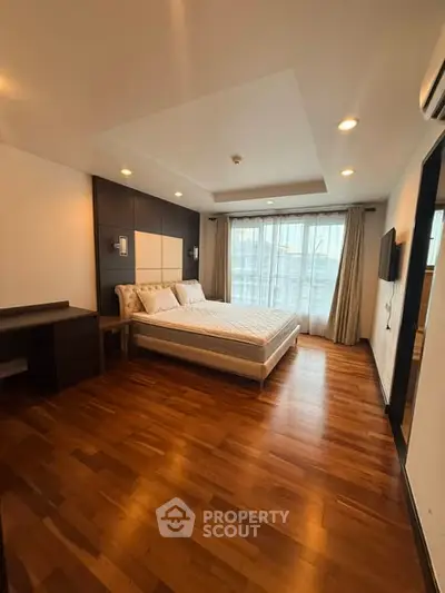 Spacious bedroom with wooden flooring and modern decor in a luxury apartment.