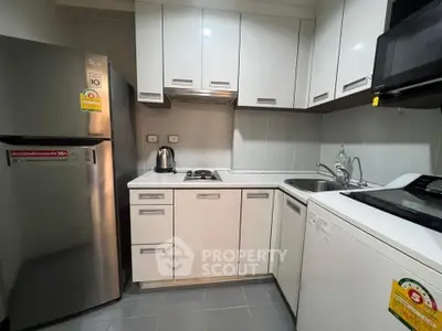 Compact modern kitchen with sleek white cabinets and essential appliances.