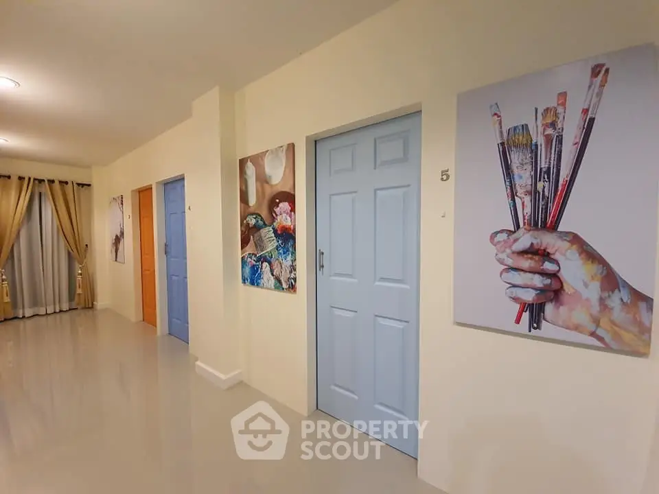 Modern hallway with colorful doors and artistic paintings on walls, featuring elegant curtains and glossy flooring.