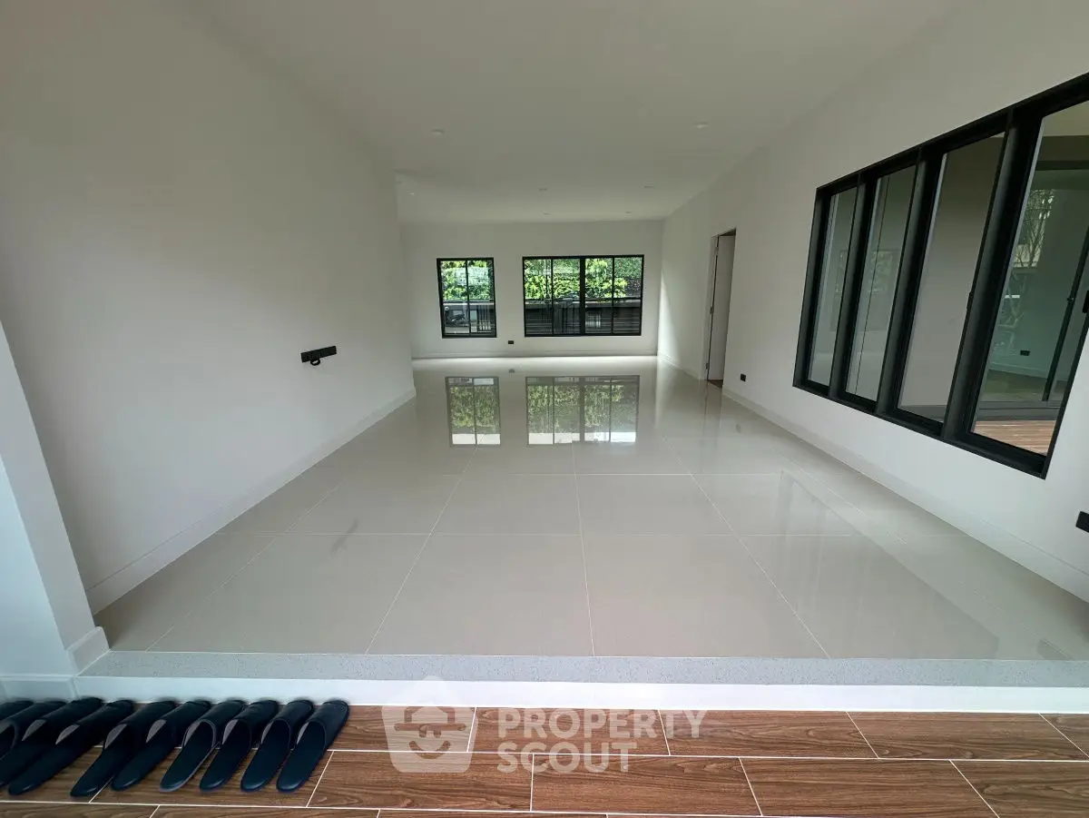 Spacious empty room with glossy tiled floor and large windows