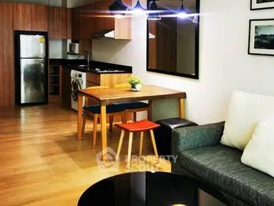 Modern open-plan living room with kitchen, featuring wooden floors and stylish furniture.