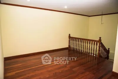 Spacious wooden-floored room with elegant railing and recessed lighting