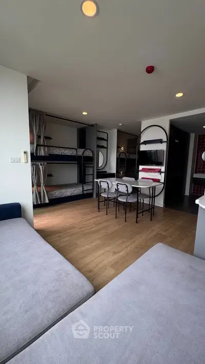 Modern living room with bunk beds and dining area, featuring sleek design and ample natural light.