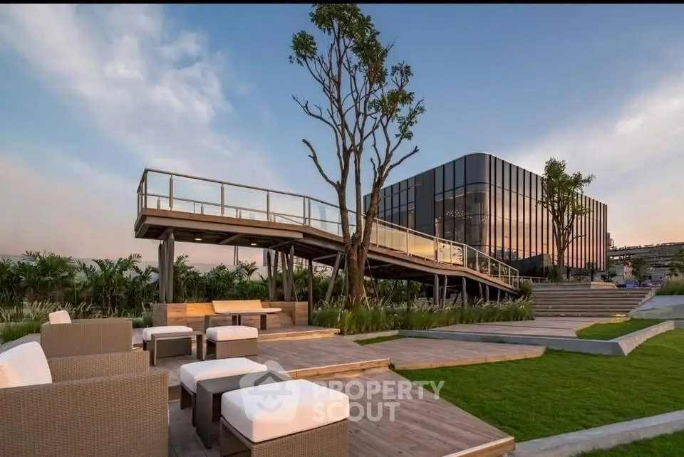 Modern architectural building with stylish outdoor seating and lush greenery at sunset.
