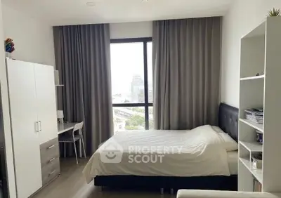 Modern bedroom with large window and stylish furnishings in a contemporary apartment.