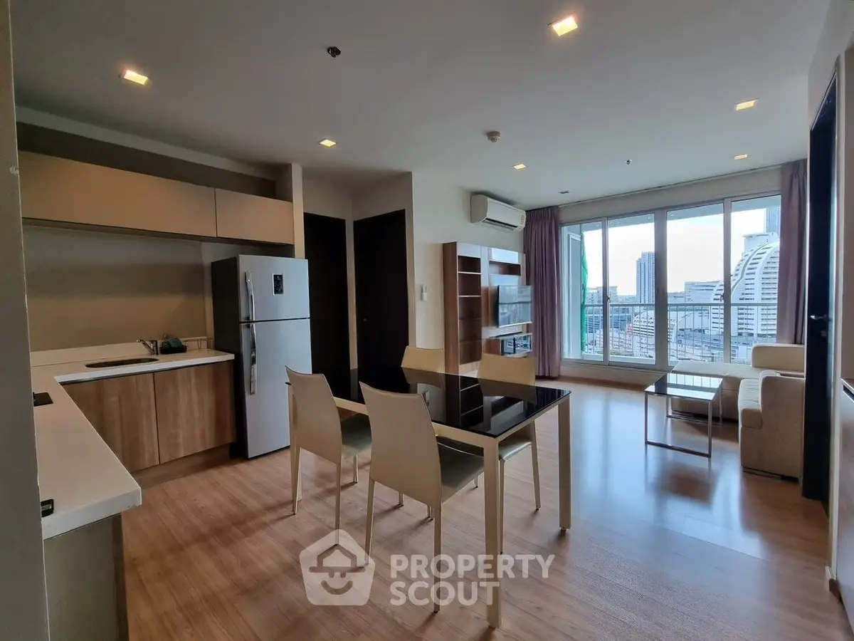 Modern open-layout living room with kitchen, featuring large windows and city view.