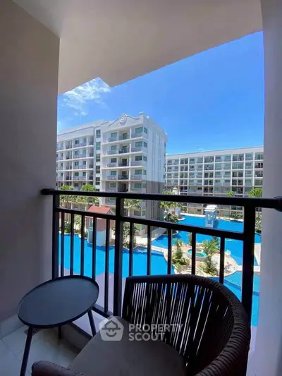 Stunning balcony view of modern apartment complex with pool and lush landscaping.