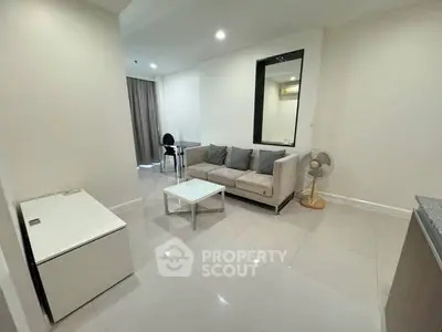 Spacious and modern living room with glossy tiled flooring, comfortable sofa set, and a large mirror adding depth and elegance.