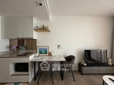 Modern living room with sleek furniture and integrated kitchen, featuring a cozy dining area and stylish decor.