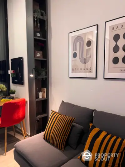 Modern living room with stylish decor, featuring a comfortable gray sofa, vibrant orange chair, and contemporary artwork.