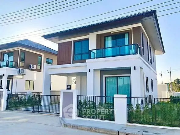 Modern two-story house with balcony and gated entrance in suburban neighborhood.