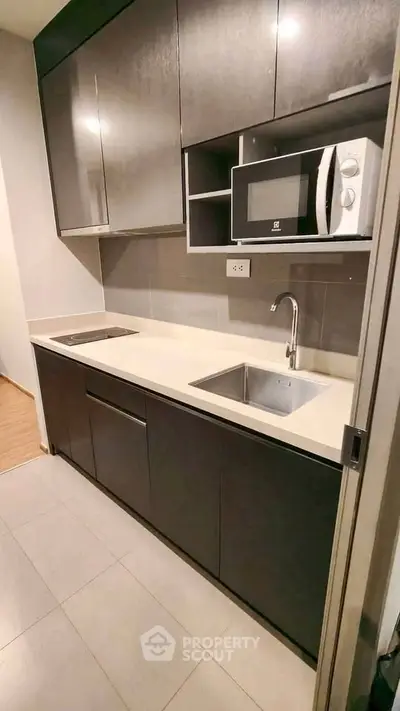 Modern kitchen with sleek cabinetry and built-in microwave in a stylish apartment.
