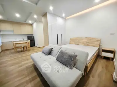 Modern studio apartment with open layout, featuring a cozy bed, stylish sofa, and sleek kitchen area.