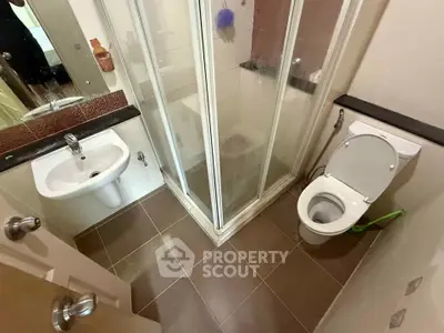 Compact bathroom with shower, toilet, and sink in modern apartment.