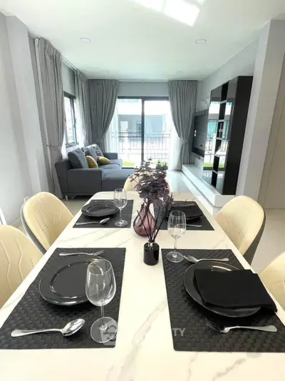Modern dining and living area with elegant table setting and cozy seating.