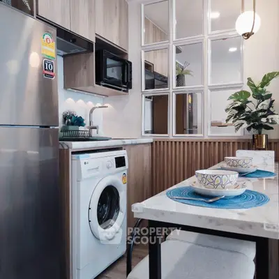 Modern kitchen with stainless steel fridge, washing machine, and stylish dining area.