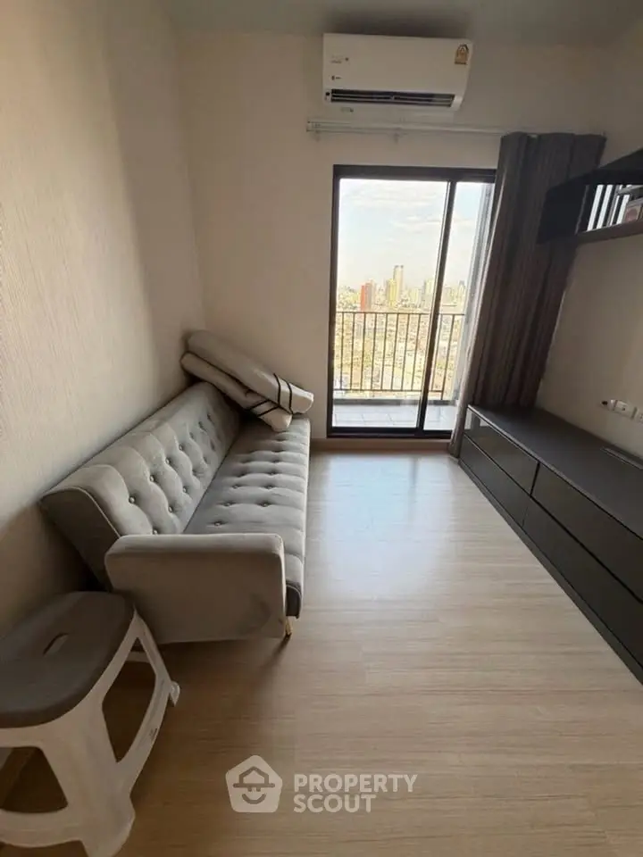 Modern living room with city view, featuring a sleek sofa and air conditioning, perfect for urban living.