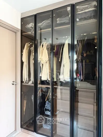 Spacious walk-in closet with glass doors and organized clothing storage