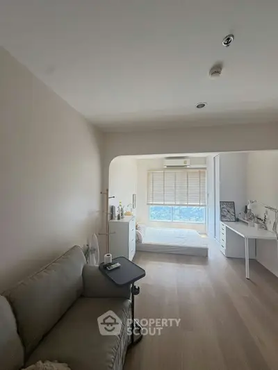 Spacious studio apartment with modern furnishings and large window view.