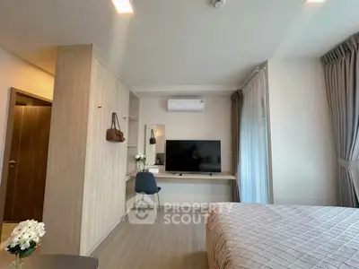Modern bedroom with stylish decor and large TV, featuring a cozy workspace and elegant lighting.