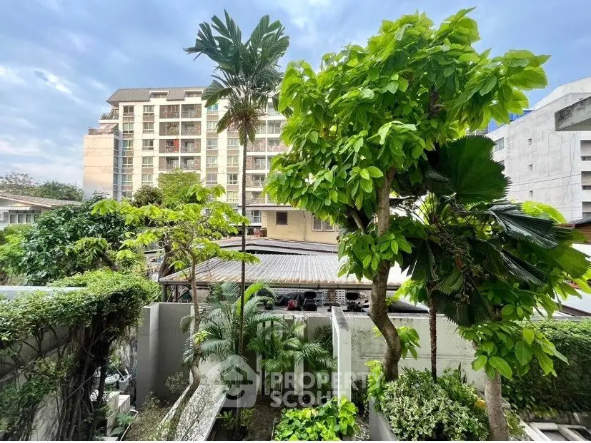 Lush garden view with tall trees and modern apartment building in the background, perfect urban oasis.