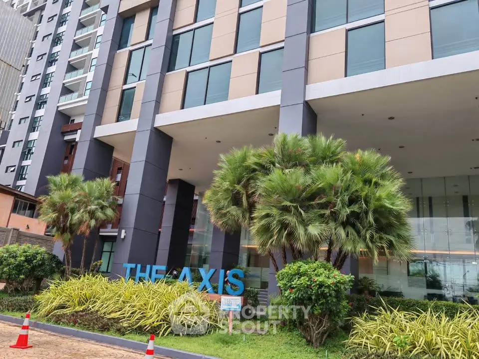 Modern building entrance with lush landscaping and sleek architectural design.