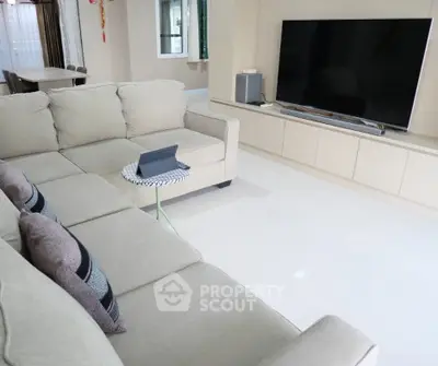 Spacious living room with modern beige sofa and large flat-screen TV, perfect for family gatherings.