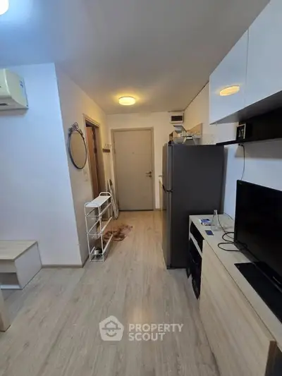 Modern apartment interior with sleek design and wooden flooring, featuring a compact kitchen and cozy living area.