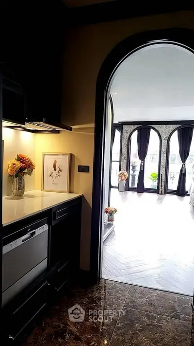 Elegant kitchen with open layout leading to a bright living area with large windows.