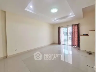 Spacious empty living room with large windows and modern ceiling lights.