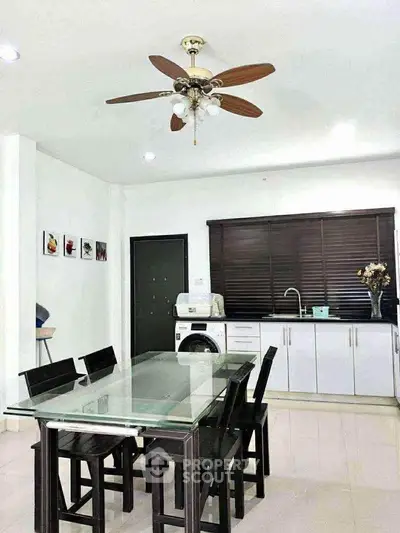 Modern kitchen with dining area, featuring sleek cabinetry and a ceiling fan for comfort.