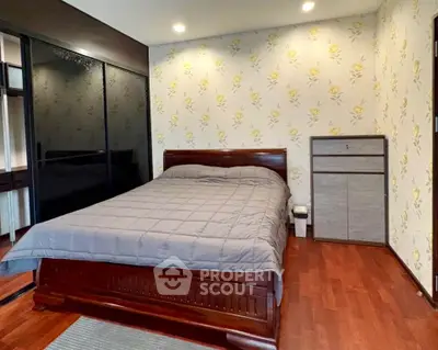 Cozy bedroom with elegant wooden flooring and stylish floral wallpaper, featuring a comfortable bed and sleek wardrobe.