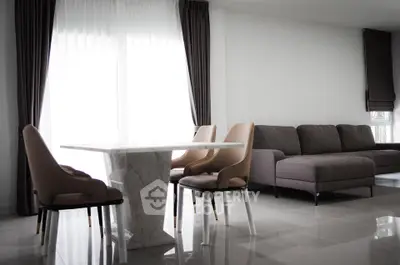 Modern living room with elegant marble dining table and cozy gray sofa, featuring floor-to-ceiling windows.