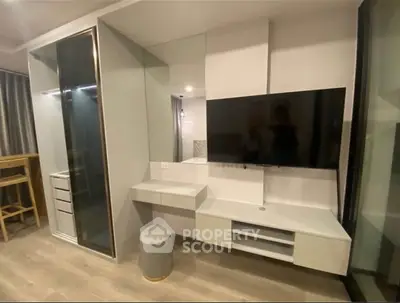 Modern living room with sleek TV unit and mirrored wardrobe in stylish apartment.