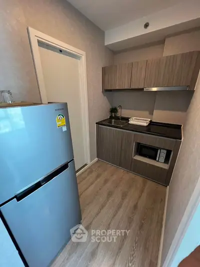 Modern compact kitchen with sleek cabinets and stainless steel fridge in cozy apartment.