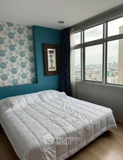 Cozy bedroom with city view, featuring large windows and stylish decor.