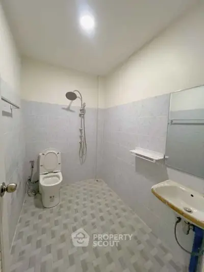 Spacious minimalist bathroom with modern fixtures and tiled walls.