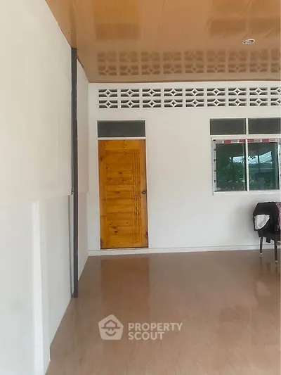 Minimalist room with wooden door and window, showcasing simple interior design.