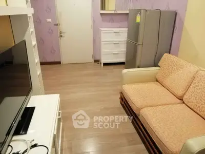 Cozy living room with modern furniture and appliances, featuring a comfortable sofa and sleek refrigerator.